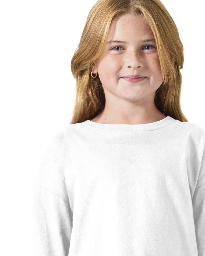 A young girl is wearing a white long sleeve t-shirt. The shirt has a simple design and features a logo.