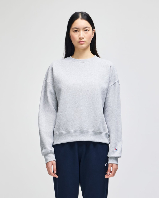 A grey women's crewneck sweatshirt with a casual fit, featuring long sleeves and a branded logo.