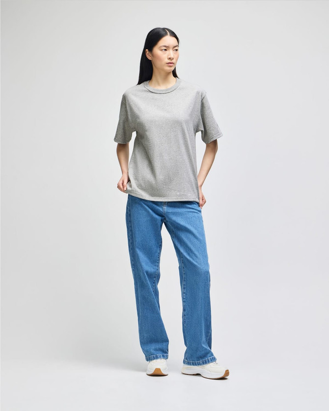 A grey Champion Adult Heritage Jersey T-Shirt worn with blue jeans, featuring a casual style and relaxed fit.