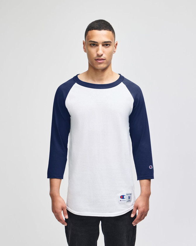 A white and navy blue raglan baseball T-shirt with three-quarter sleeves and a logo on the sleeve.
