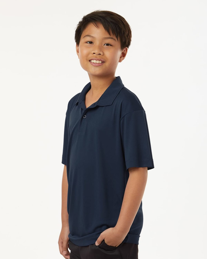 A youth performance polo in navy blue, featuring a collar and short sleeves, worn by a smiling boy.