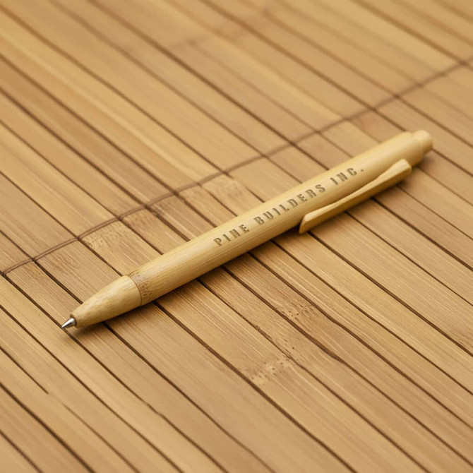 A bamboo pen with a natural finish, featuring a clip and branding. The background is made of bamboo material.