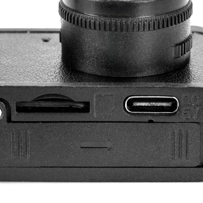 A black mini camera featuring a lens, USB-C port, and a memory card slot. It has a textured surface.