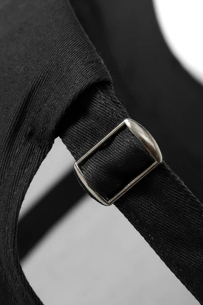 A close-up of a black cap featuring a metal buckle and strap detail.