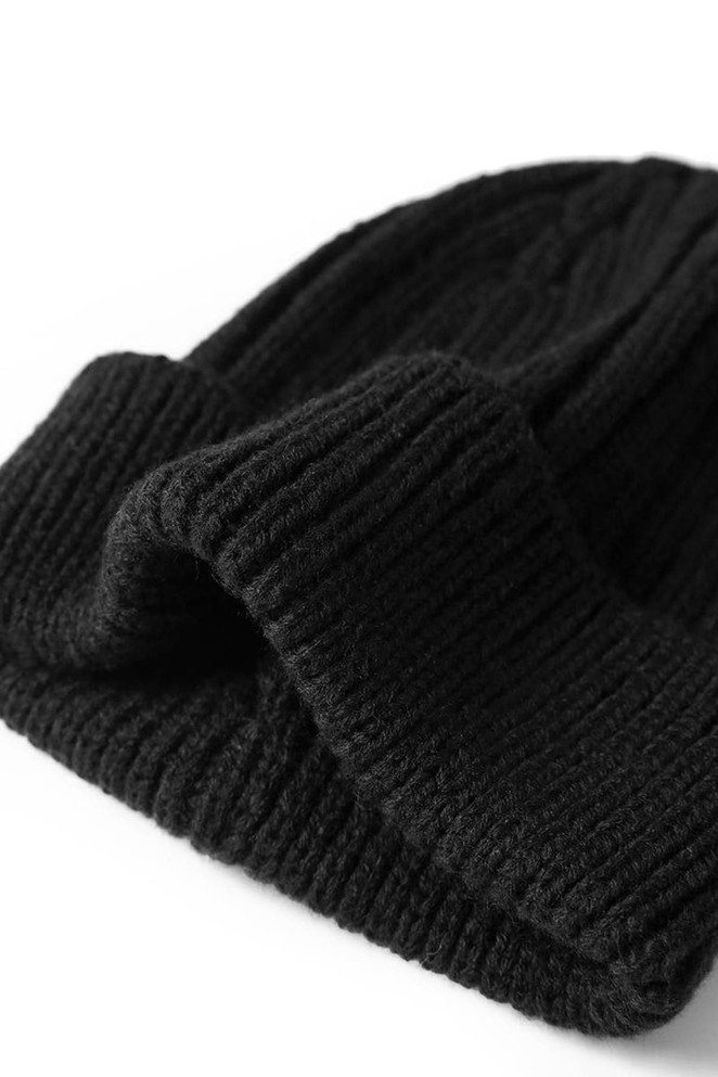 A black knitted beanie with a folded cuff, featuring ribbed texture and a subtle logo.