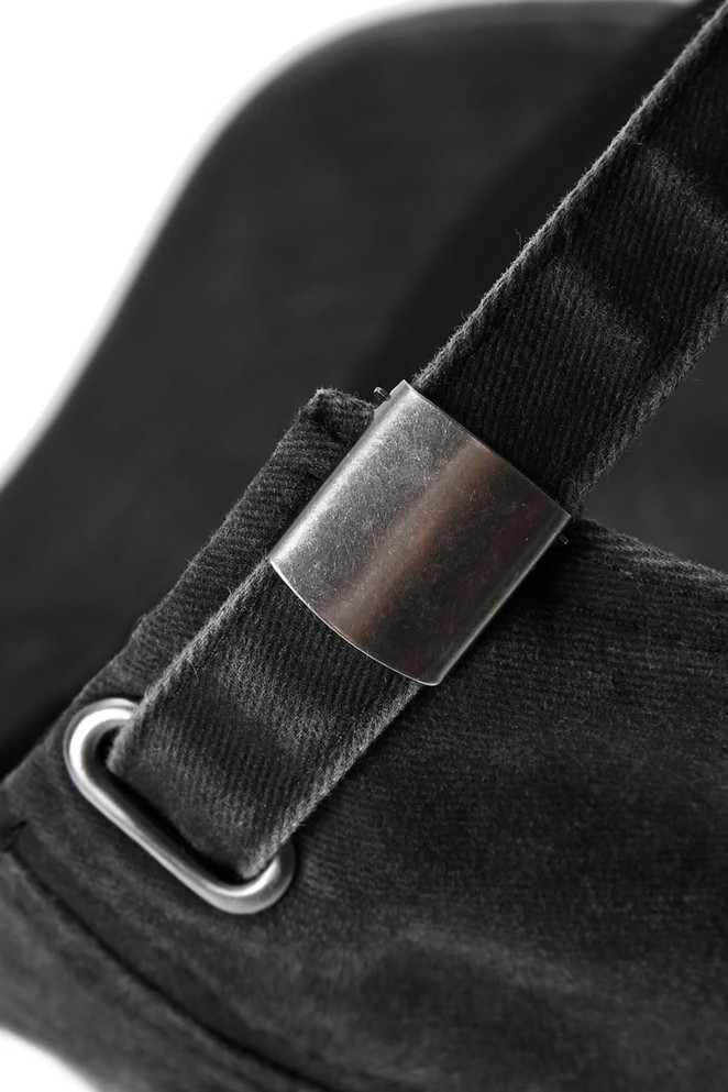 A close-up of a black cotton drill cap featuring a metal adjustment buckle and strap.