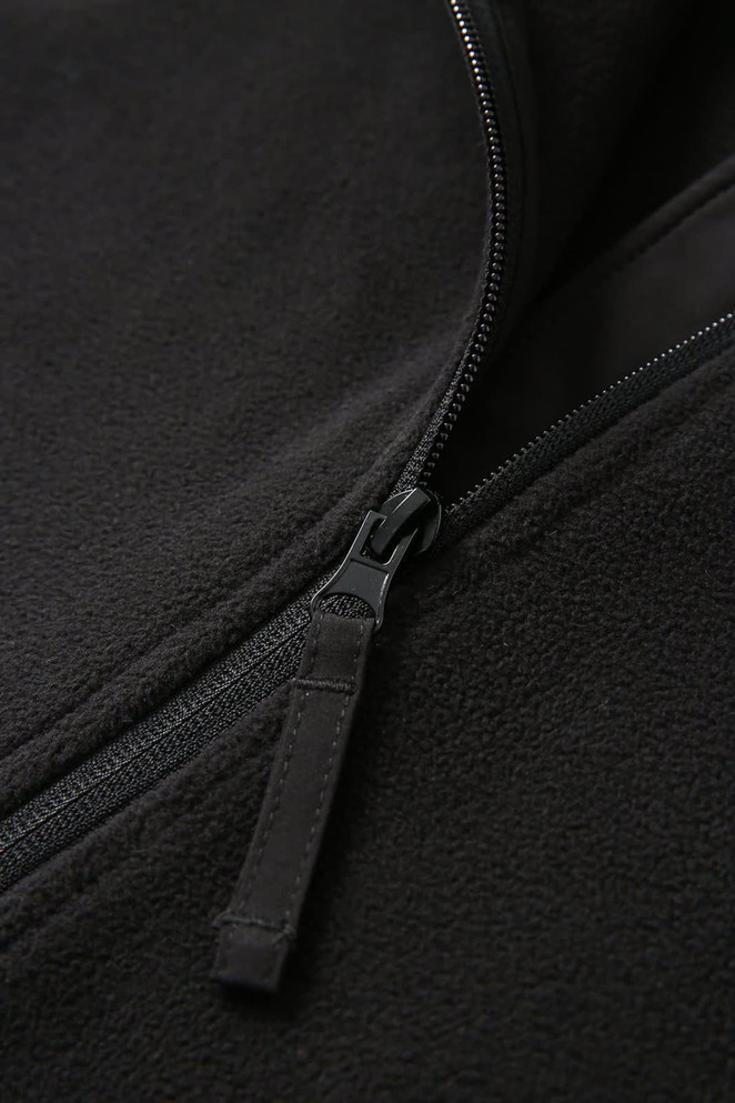 A close-up of a black polar fleece half zip top, featuring a smooth zipper detailing.