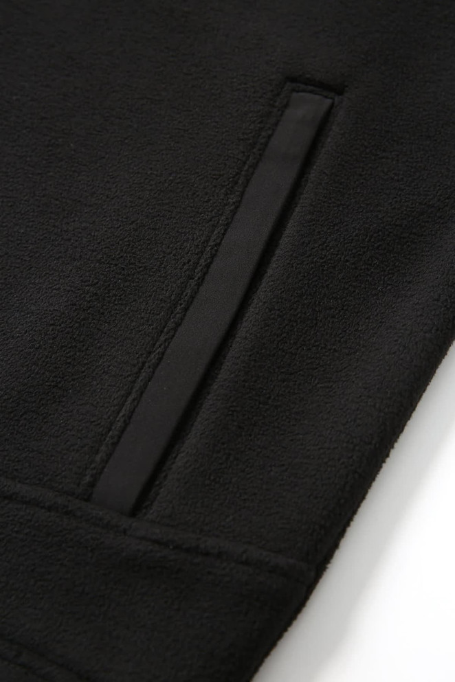 A close-up of a black polar fleece half zip top featuring a side pocket and a smooth fabric finish.