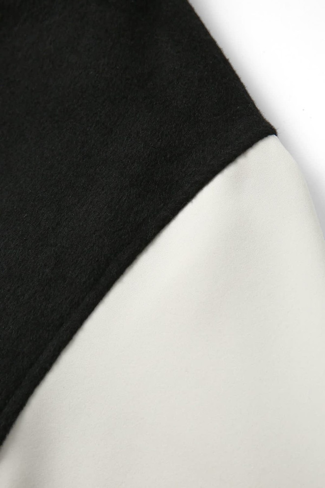 A close-up of a men's/unisex wool blend varsity jacket with black and cream fabric. It features a branding logo.