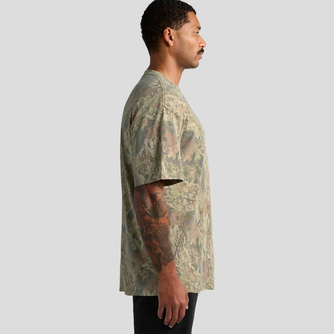 A side view of a man wearing a heavy faded camo T-shirt in various shades of green and brown. The shirt has a logo.