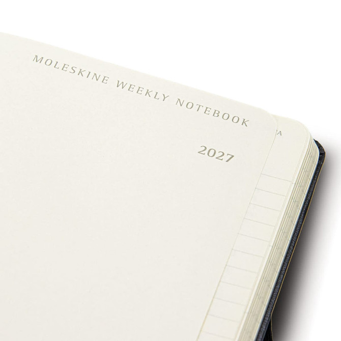 A Moleskine 2027 weekly planner in navy blue with blank pages and a branding logo on the cover.