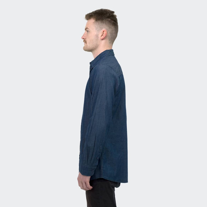 A denim button-up shirt in dark blue, featuring a collar and long sleeves, displayed on a model in profile.