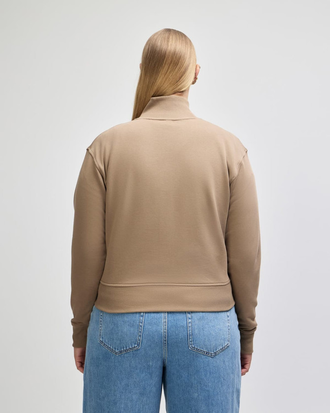A women's full-zip jacket in tan, featuring a casual design and a logo on the back.