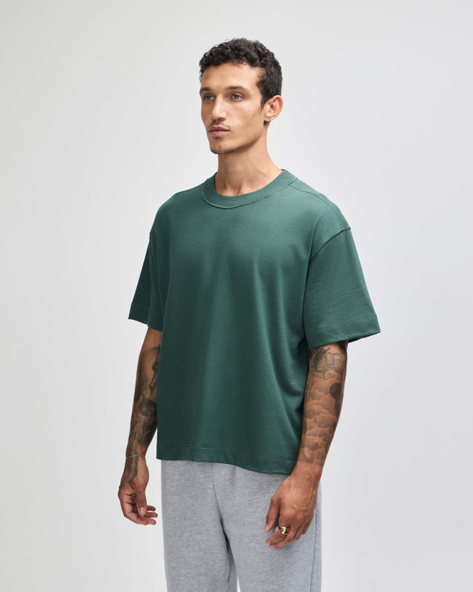 A boxy unisex T-shirt in a deep green colour, featuring short sleeves and a relaxed fit.