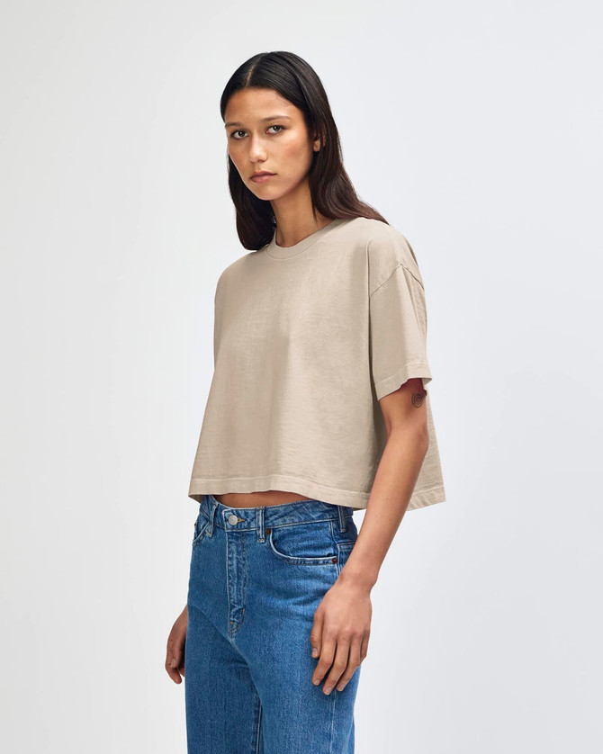 A heavyweight cotton women's crop boxy T-shirt in a neutral beige colour, featuring a relaxed fit and a branding logo.