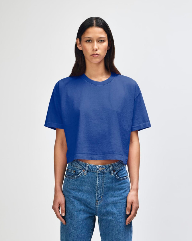 A blue, heavyweight cotton women's crop boxy T-shirt displayed on a model, featuring a logo.