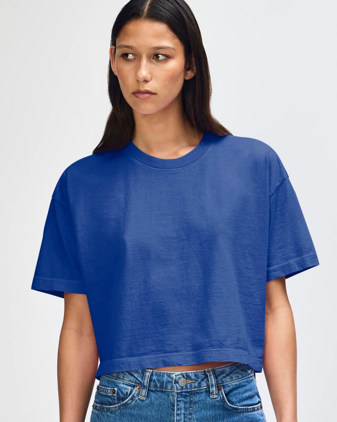 A blue heavyweight cotton women's crop boxy T-shirt worn by a model, featuring a simple design and logo.