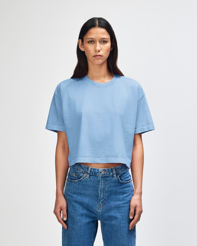 A blue cropped boxy t-shirt made from heavyweight cotton, featuring a logo on the fabric.