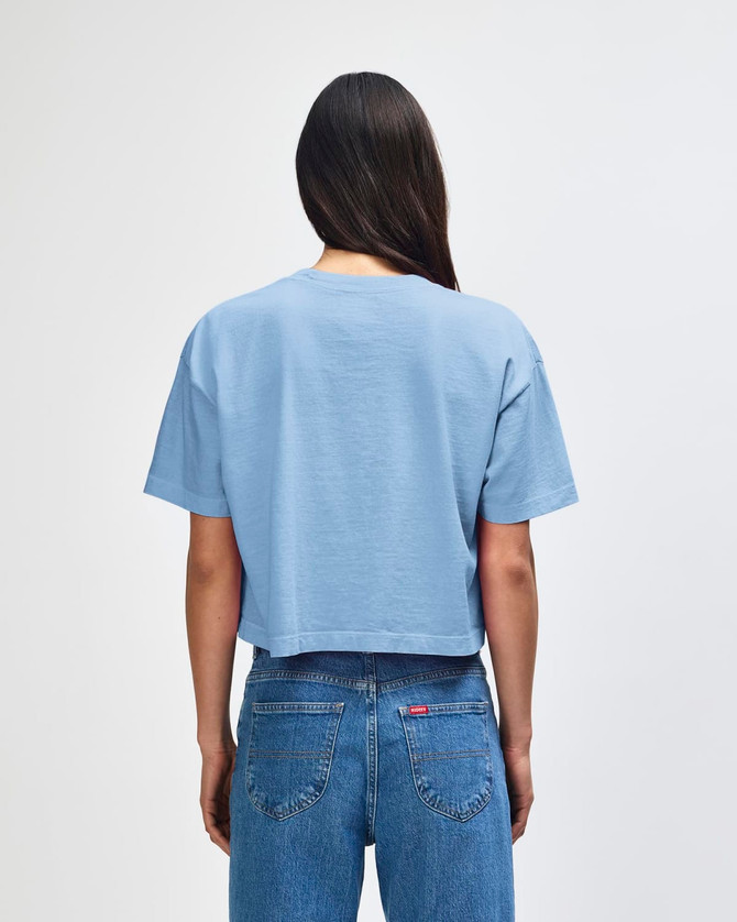 A blue crop boxy t-shirt with a back view, featuring a relaxed fit and short sleeves. There is a logo present.