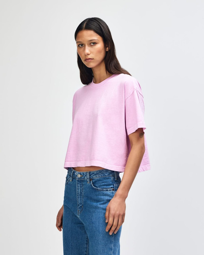 A pale pink women's crop boxy T-shirt, featuring a relaxed fit and short sleeves, worn with blue jeans.