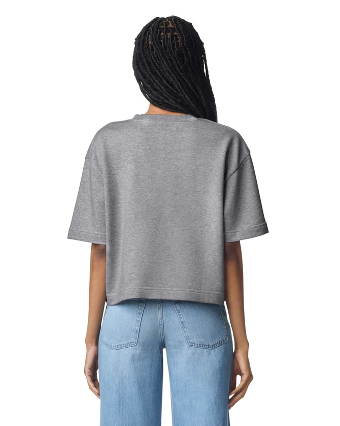 A mid-length, boxy women's top in grey, featuring short sleeves and a relaxed fit. It has a logo on the back.