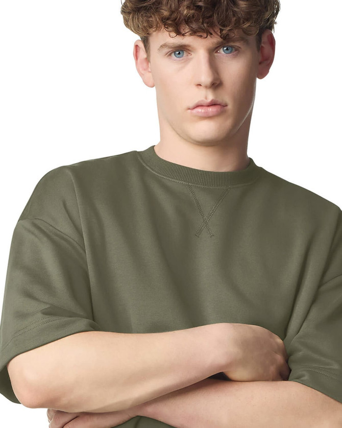 A unisex oversized boxy top in olive green, featuring short sleeves and a relaxed fit. Contains a logo.