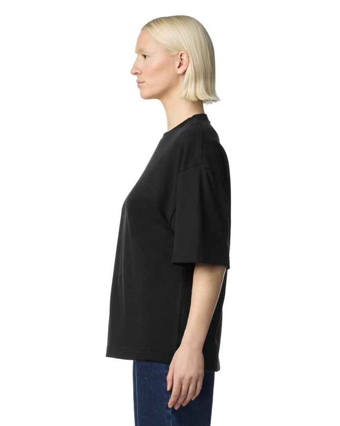 A black oversized boxy top with short sleeves displayed on a model from the side, featuring a logo.