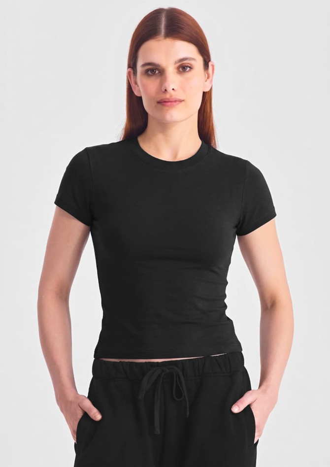 A fitted black women's baby tee with short sleeves, worn by a model against a grey background.