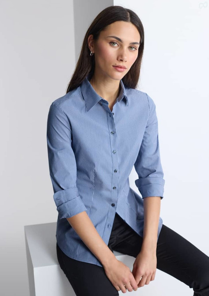 A women's long sleeve shirt in blue and white stripes, featuring a collar and rolled sleeves. It has a brand logo.