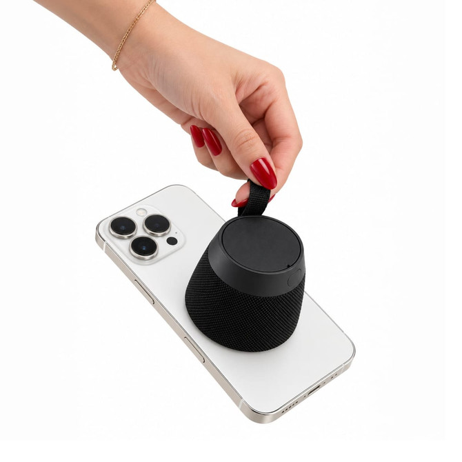 A black portable speaker being attached to a smartphone, showcasing a sleek design and convenient size.