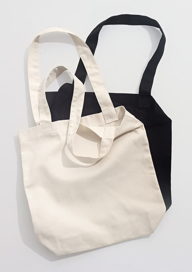 Two canvas tote bags, one in cream and one in black, featuring long handles and a simple design.