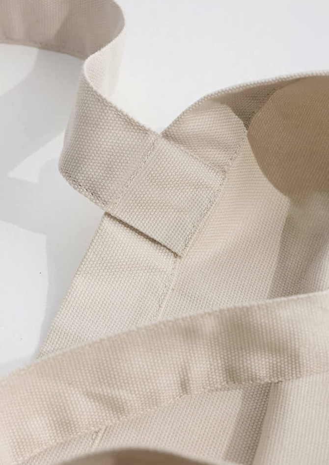 A beige canvas tote bag featuring sturdy straps and a simple design. The bag has a visible logo.