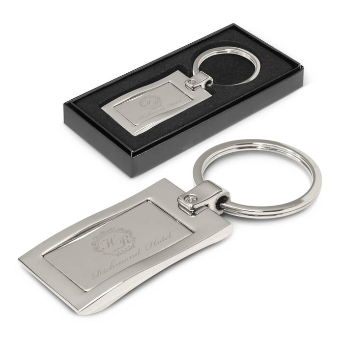 A silver metal key ring in a black presentation box with an engraved design.