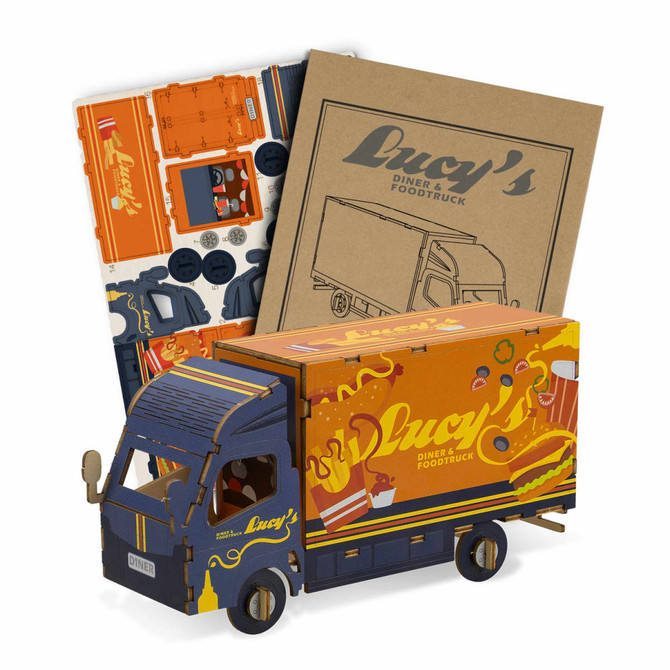 A small wooden model of a truck in blue and orange, with accompanying cardboard pieces for assembly.