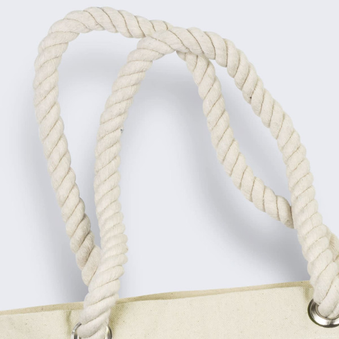 A close-up of the twisted, cream-coloured rope handles of a tote bag featuring silver eyelets.