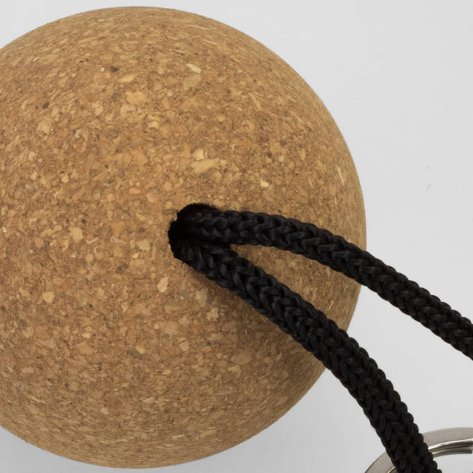 A round cork floating key ring with a black braided cord attached.