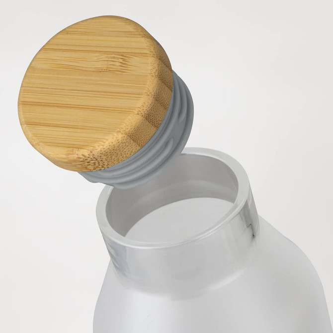 A drink bottle with a transparent body and a bamboo lid, featuring a grey seal.