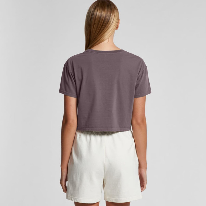 A back view of a women's faded crop tee in muted grey, paired with light cream shorts. The shirt features a logo.