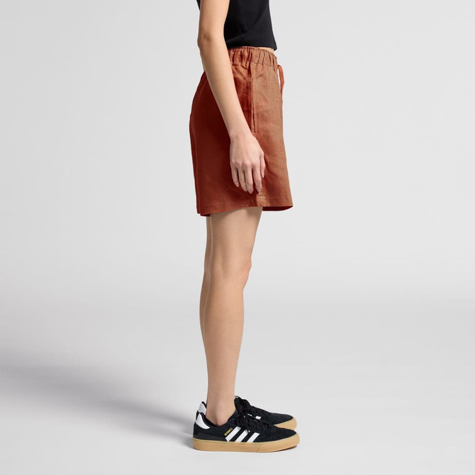 Linen shorts in a warm terracotta colour, with an elastic waistband and relaxed fit, styled with black sneakers.