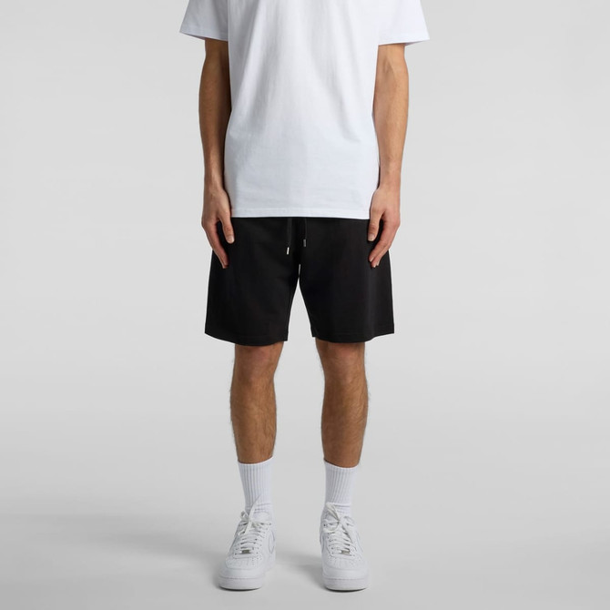 A person wearing black sports shorts styled with a plain white t-shirt and white sneakers.