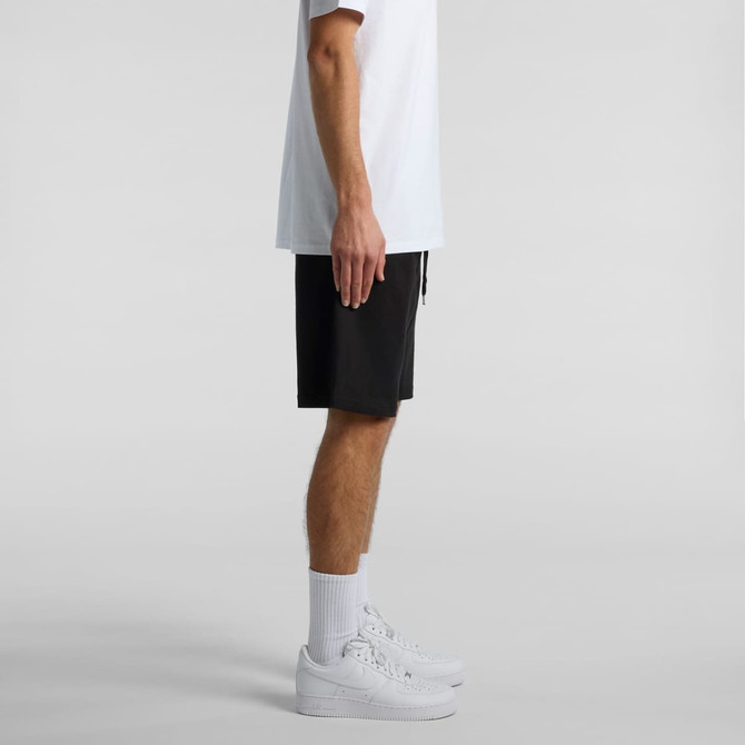 A pair of black sports shorts featuring a drawstring, showcased with white sneakers and a white t-shirt.