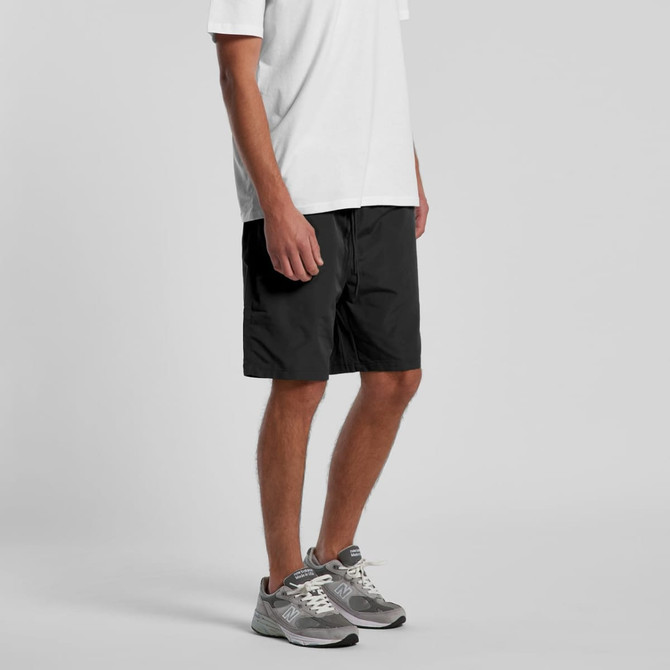 Active training shorts in black, featuring pockets and a logo, worn with a white T-shirt and grey sneakers.