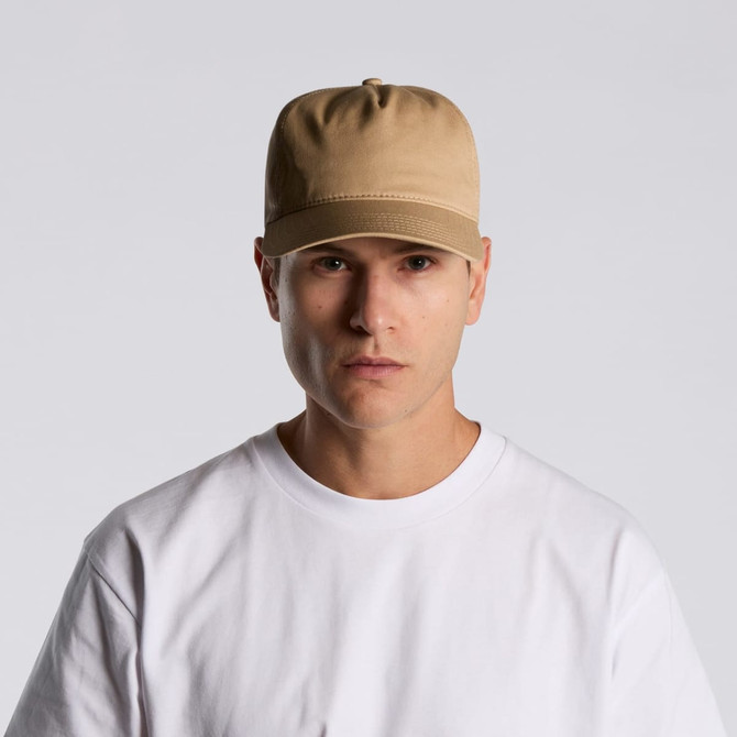 A beige soft cap worn by a model, featuring a simple design and a prominent logo.