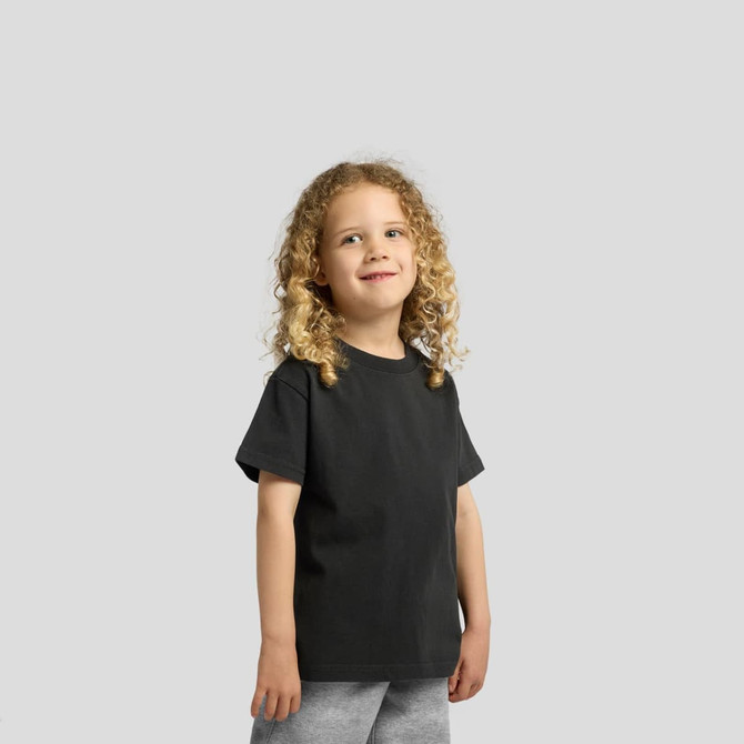 A child wearing a black heavy faded tee, paired with grey shorts, smiling at the camera.