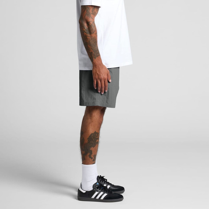 Swim shorts in grey, featuring side pockets, worn with a white t-shirt and black sneakers.