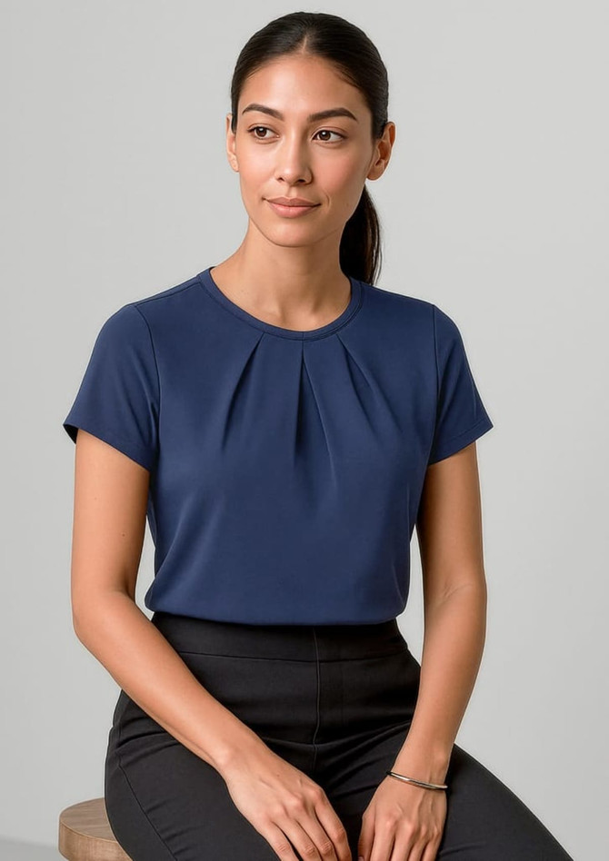 A navy short sleeve top with pleats, featuring a logo, displayed on a model.