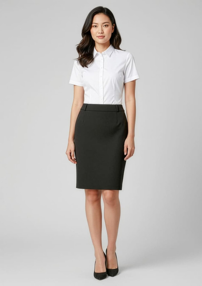 A woman wearing a fitted black skirt and a white collared shirt, standing against a neutral background.