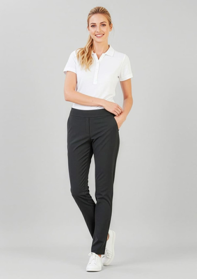 A woman stands in fitted black stretch pants paired with a white polo shirt and white sneakers.