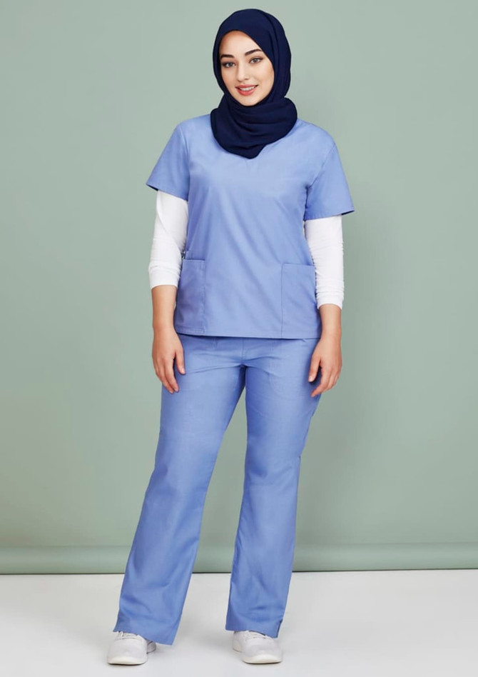 A model wearing light blue classic women's bootleg scrub pants paired with a matching scrub top and a navy hijab.