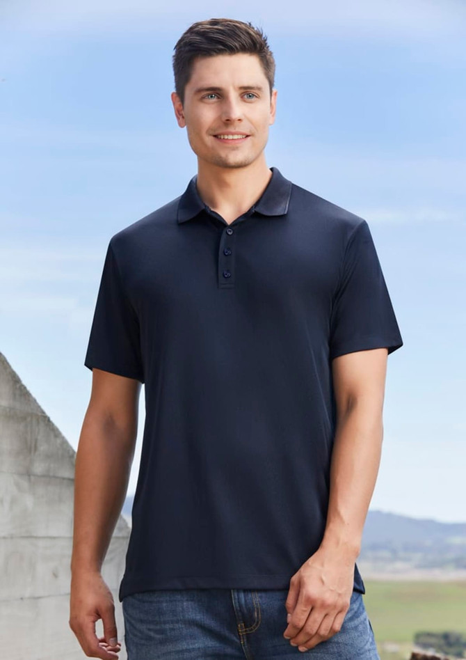 A navy blue men's short sleeve polo shirt, featuring a collar and buttons, worn by a smiling male model outdoors.